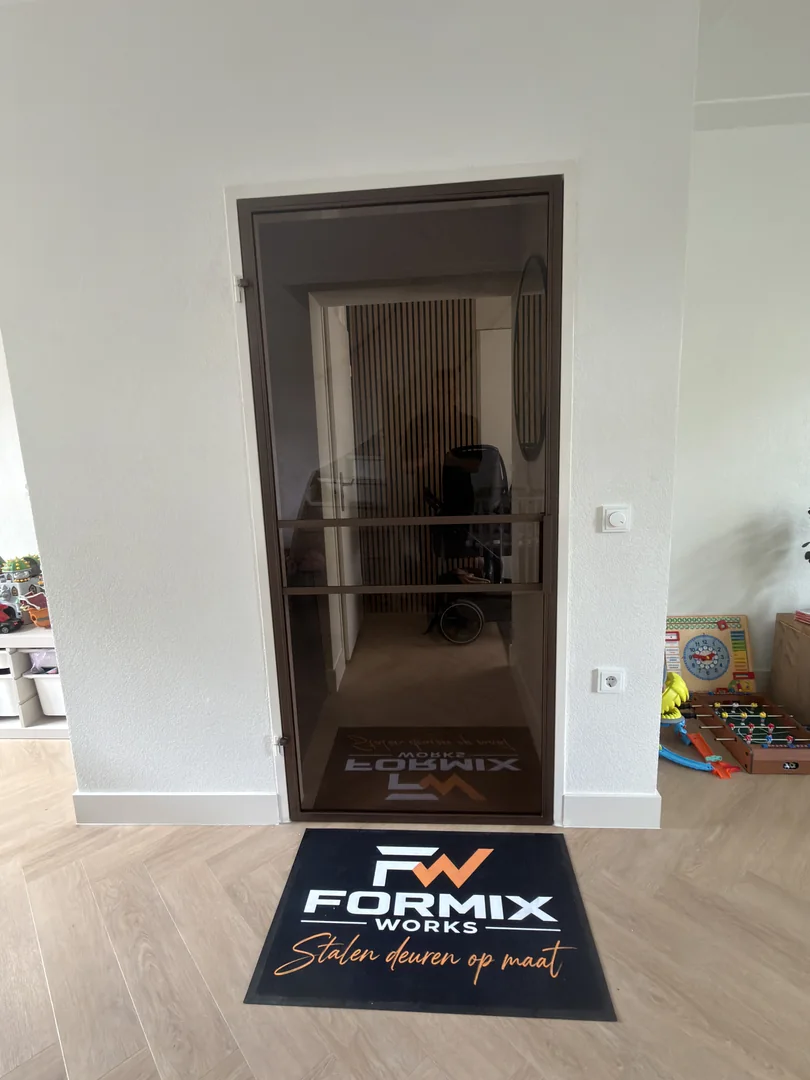 Stalen deur met brons glas in een bestaand wit kozijn bij een woning in Oss.