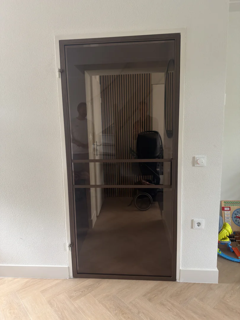 Vooraanzicht van een stalen deur met brons glas en Noble Bronze fijnstructuur in Oss.