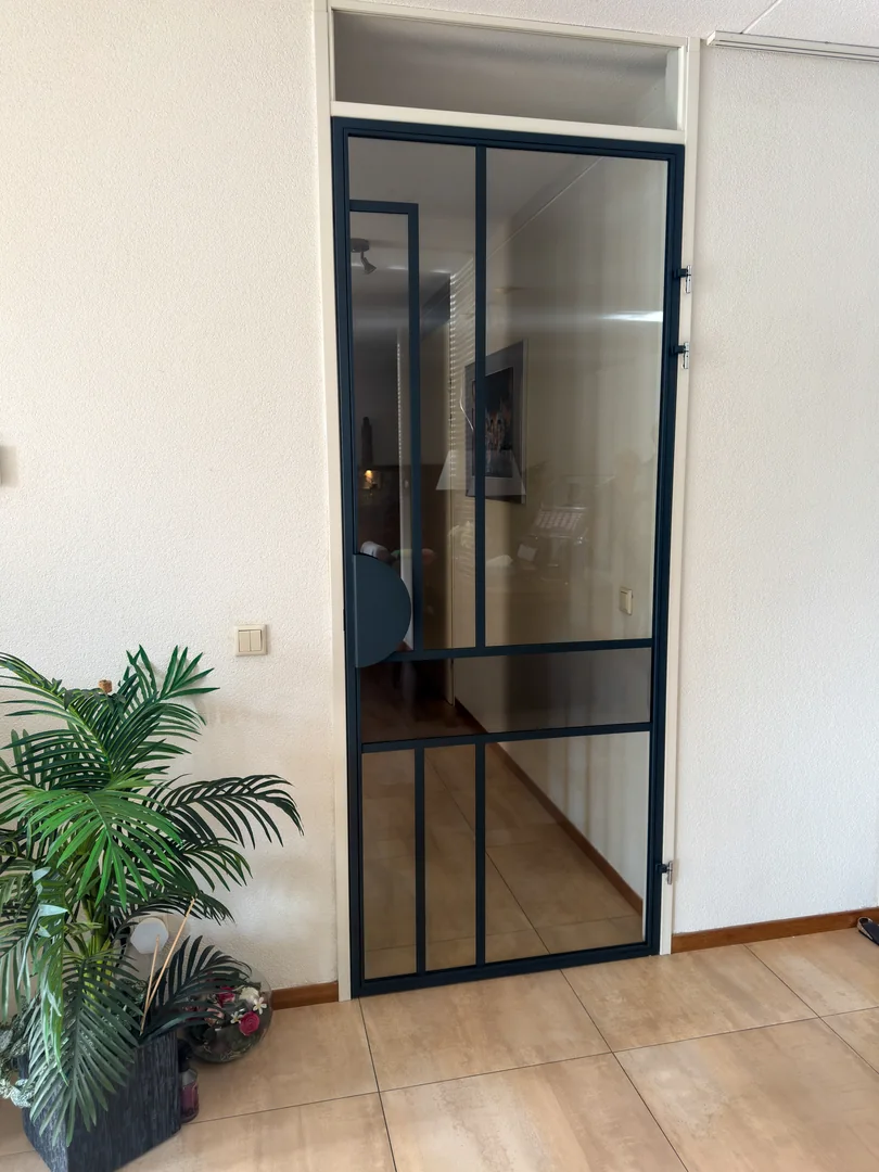 Vooraanzicht van een stalen deur in Sint-Michielsgestel met antraciet coating en een combinatie van helder en smoke glas.